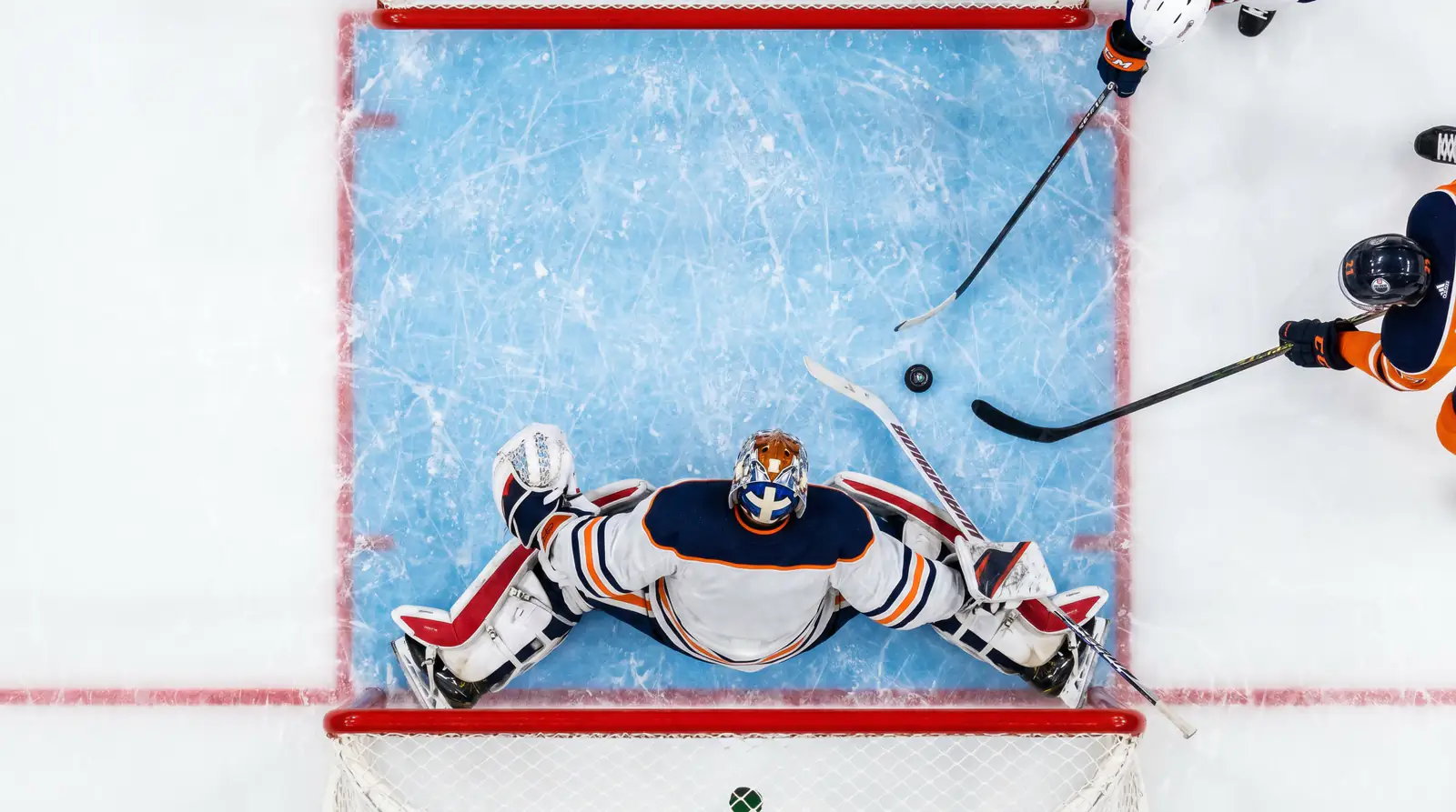 Overhead view of an NHL goalmouth with the puck near the crease and defenders scrambling
